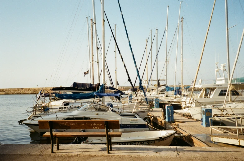 boats parked along side a pier, with one bench facing the water