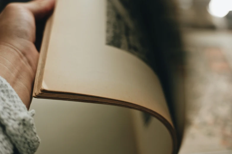 a hand holding a book in the middle of its palm