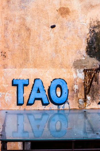 graffiti on the wall that reads, tao above a bench