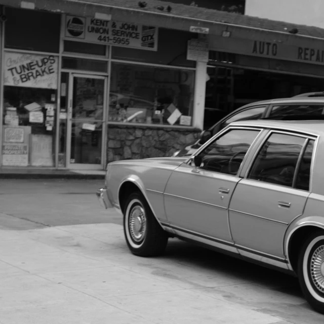 a silver car sits parked outside of a storefront