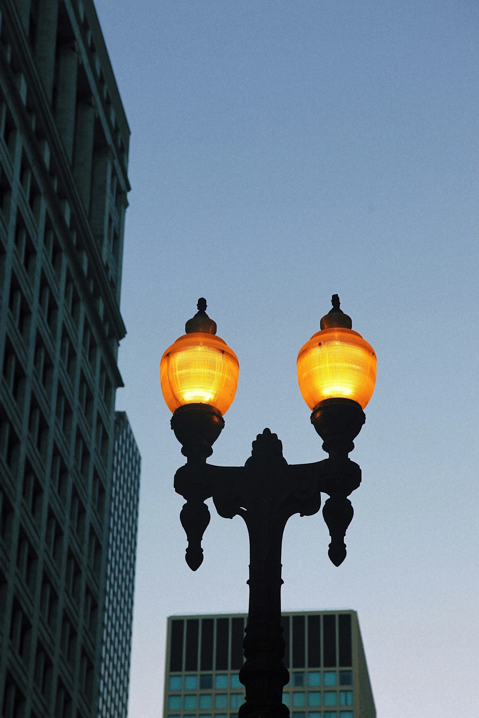 there are two lights on the pole by a building