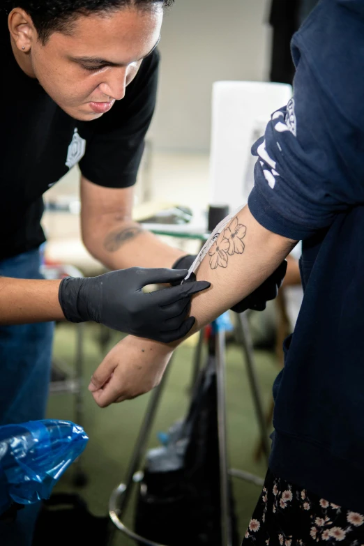 two people with arm tattoos looking down at soing