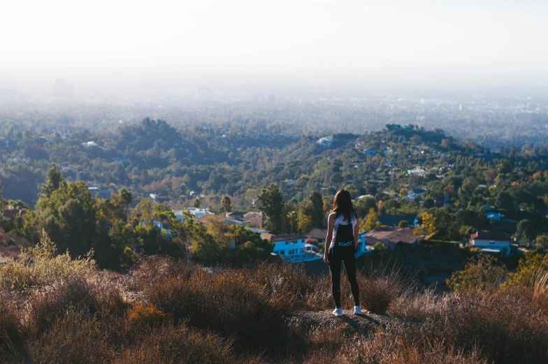 the woman looks at the town from a hill top