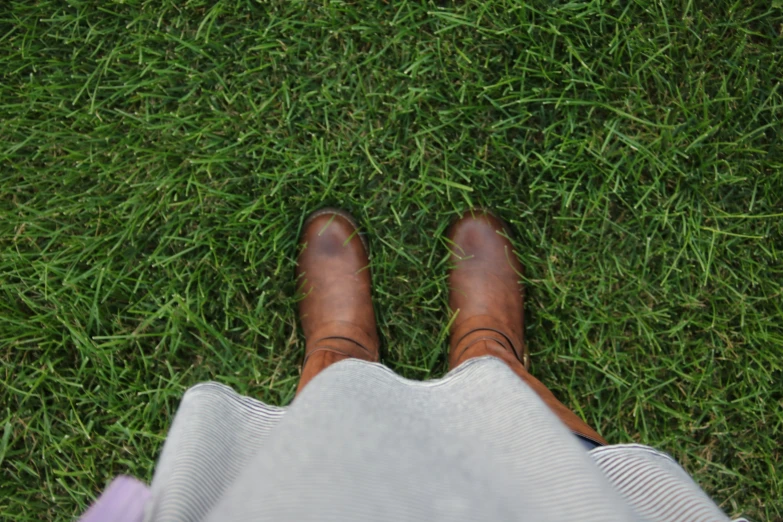 the man's feet are wearing shoes and standing in front of grass