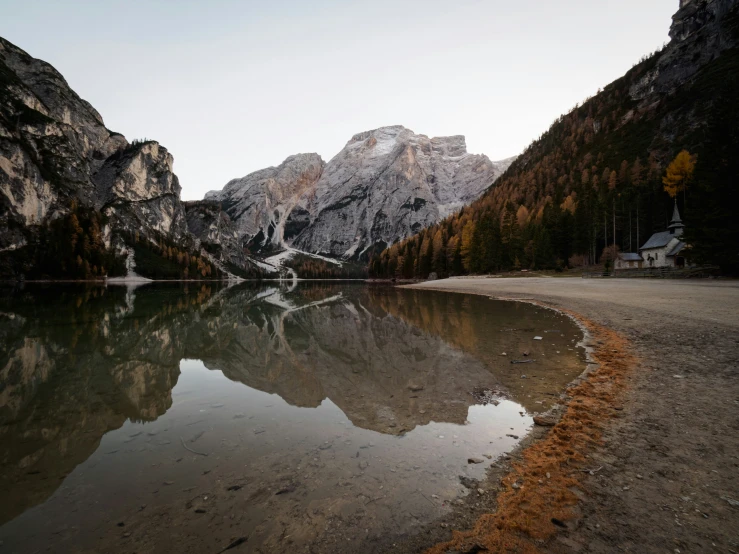 a mountain side with a lake surrounded by trees