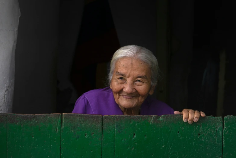 a woman leans over a green wooden door