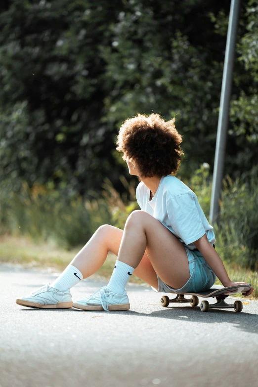 a girl in shorts sitting on her skateboard