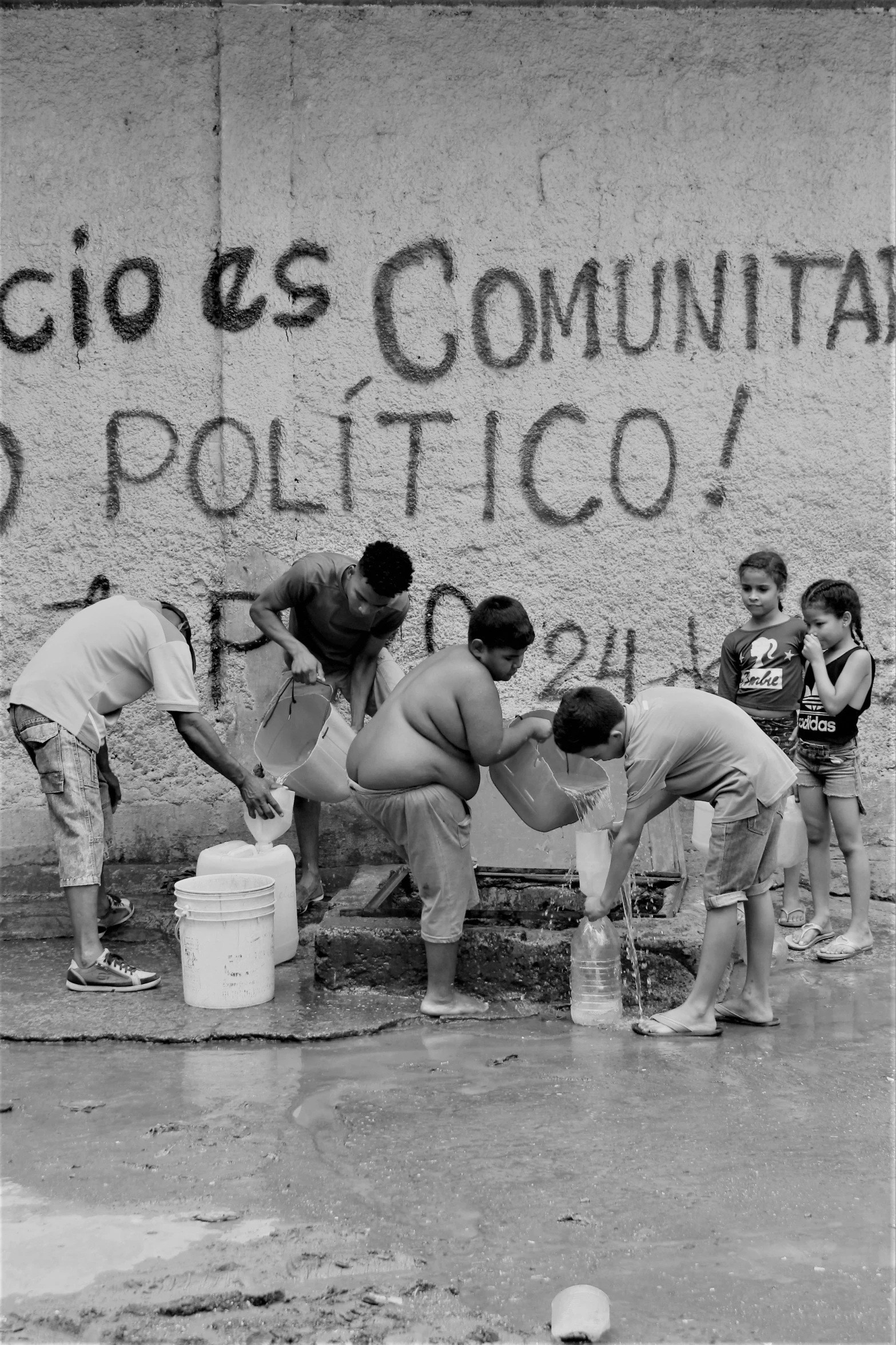 men and children wash out in front of a graffiti