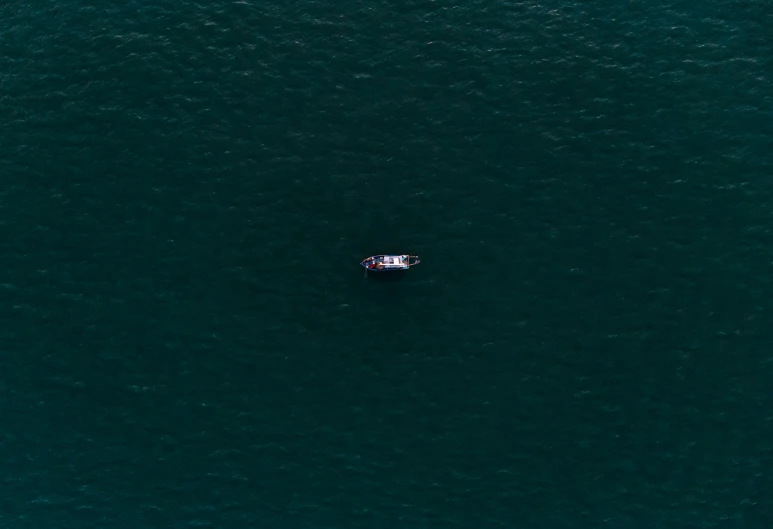 a lone boat floats on top of the blue water
