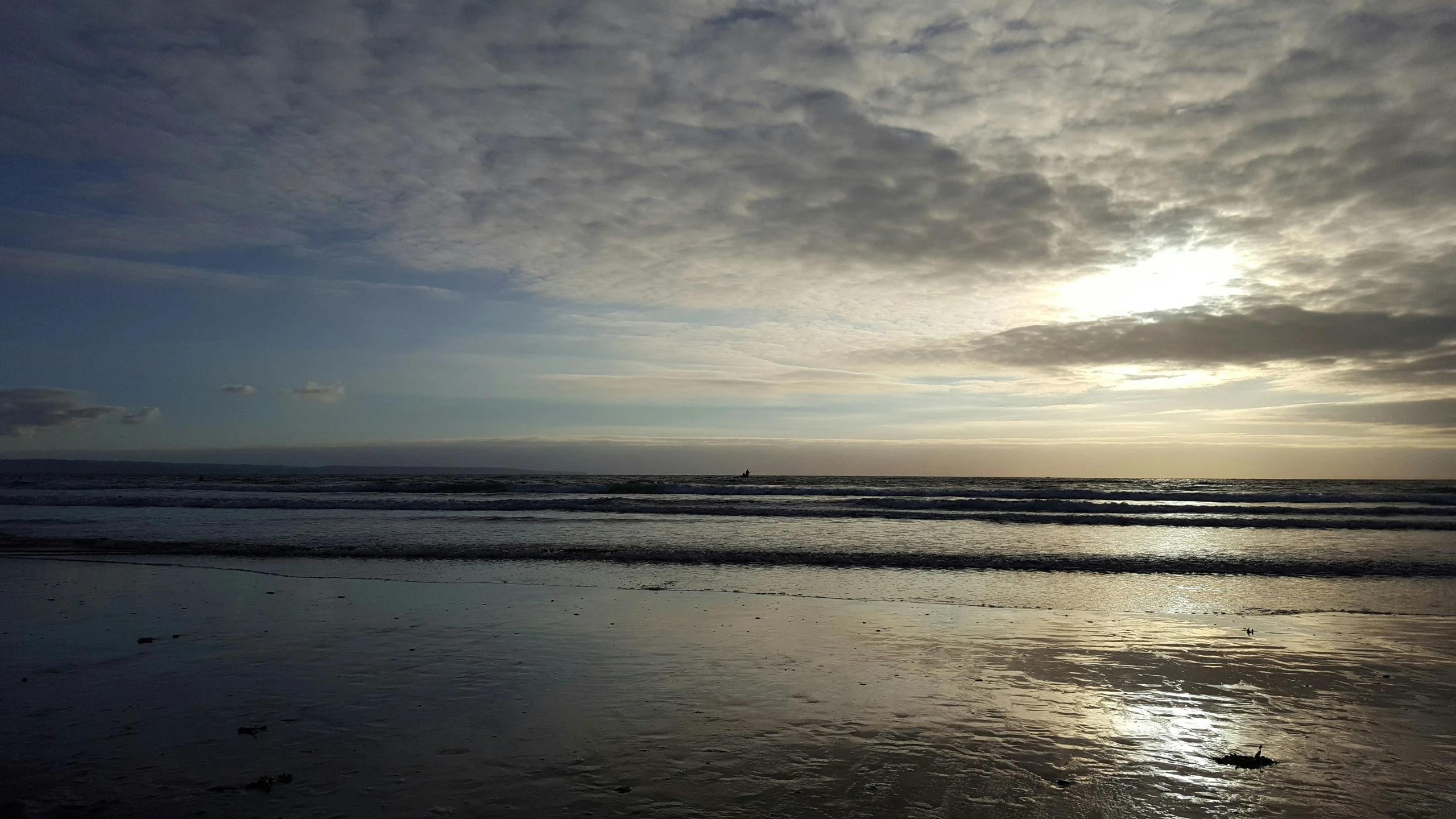 a person standing on the beach in front of the ocean and sunset