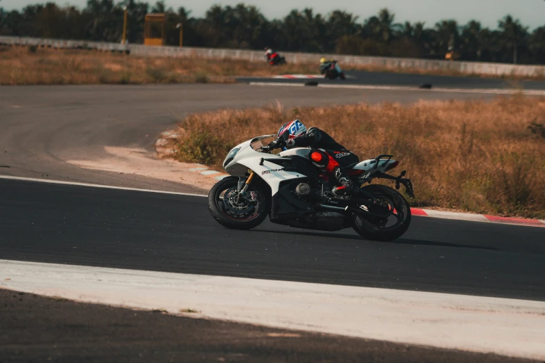 two men riding their motorcycles around the track