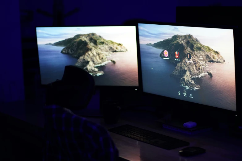a man sitting in front of two monitors while playing a game