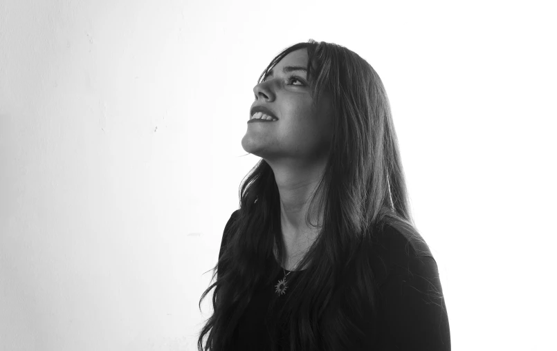 a young woman in black looking up into the sky