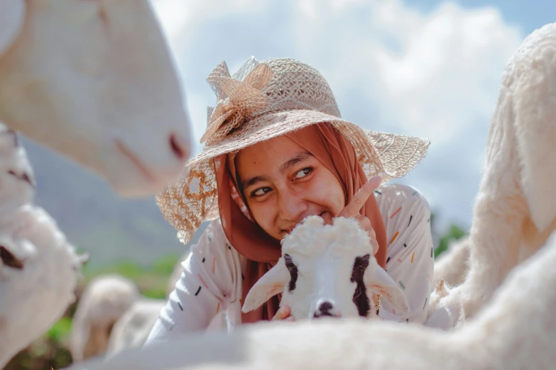 the girl in the straw hat is touching the face of some sheep