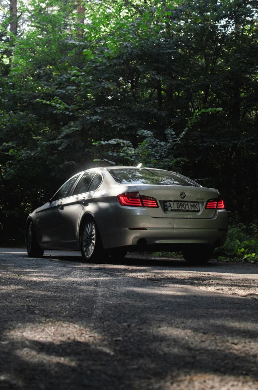 a silver car parked on a street with a forest in the background