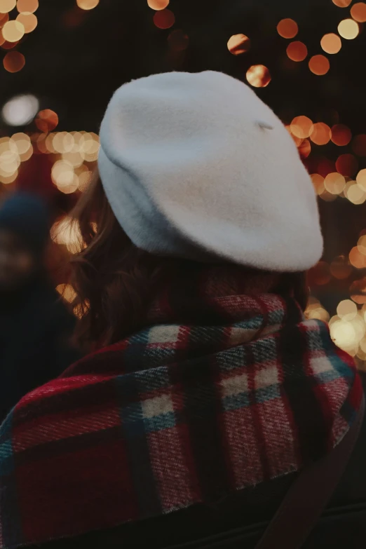 a person wearing a hat standing in front of christmas lights