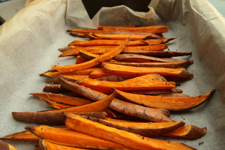 sliced sweet potatoes in a tray lined up on a paper