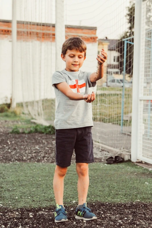 the boy holds up his tennis racquet in front of a fence