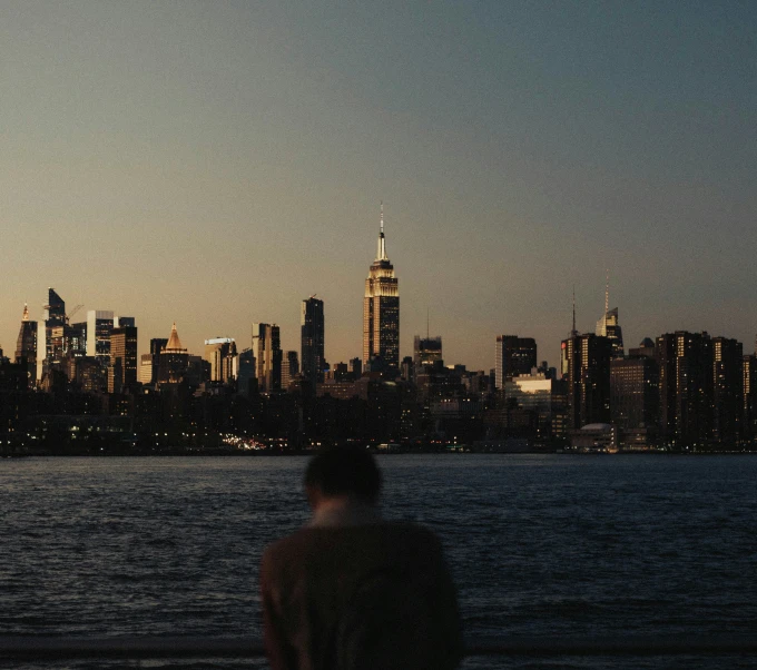 a person looking out at a city skyline from the water