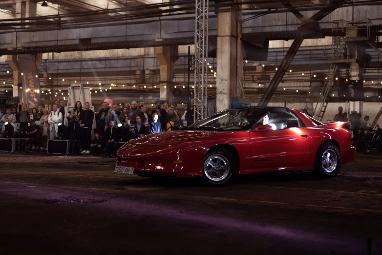 a sports car drives down a darkened street in front of people