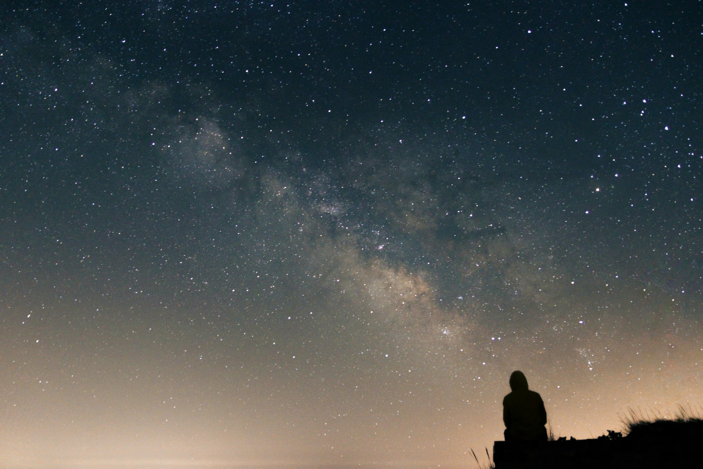 the silhouette of a man standing near a cliff in front of stars