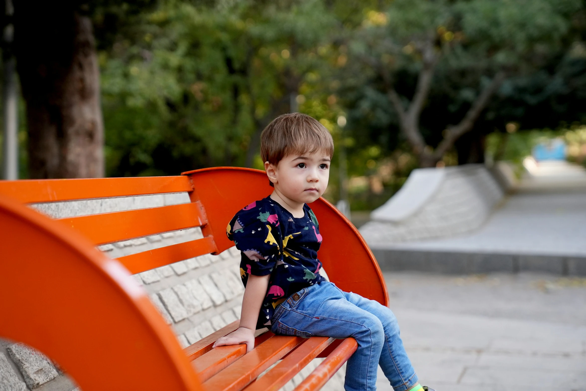 the small child sits on the bench next to his parents