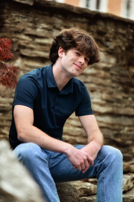 a man sitting in front of a rock wall