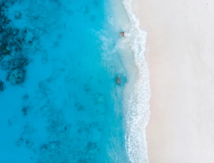 a long white beach with people laying in the water