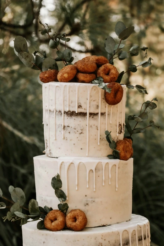 a triple layer cake with white icing and doughnuts