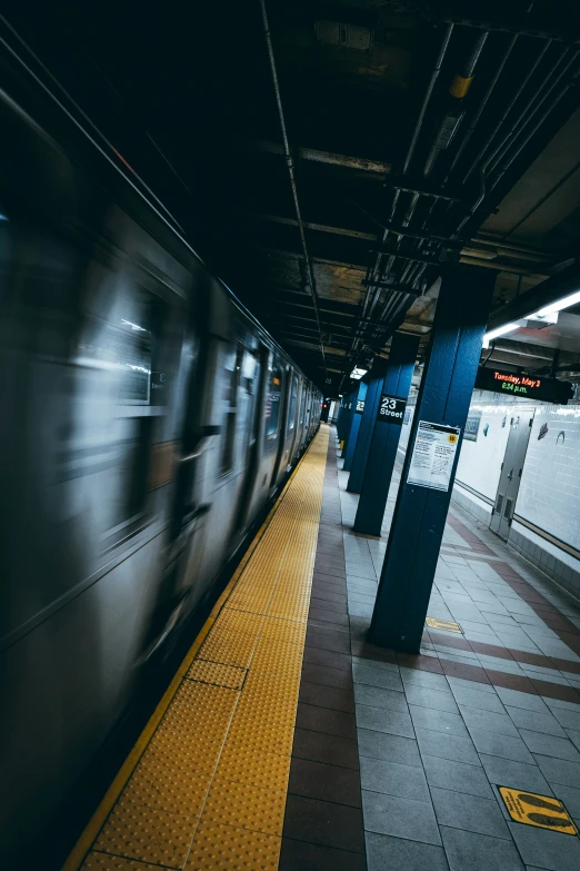 an empty train station in dark, with a subway platform and yellow tiles