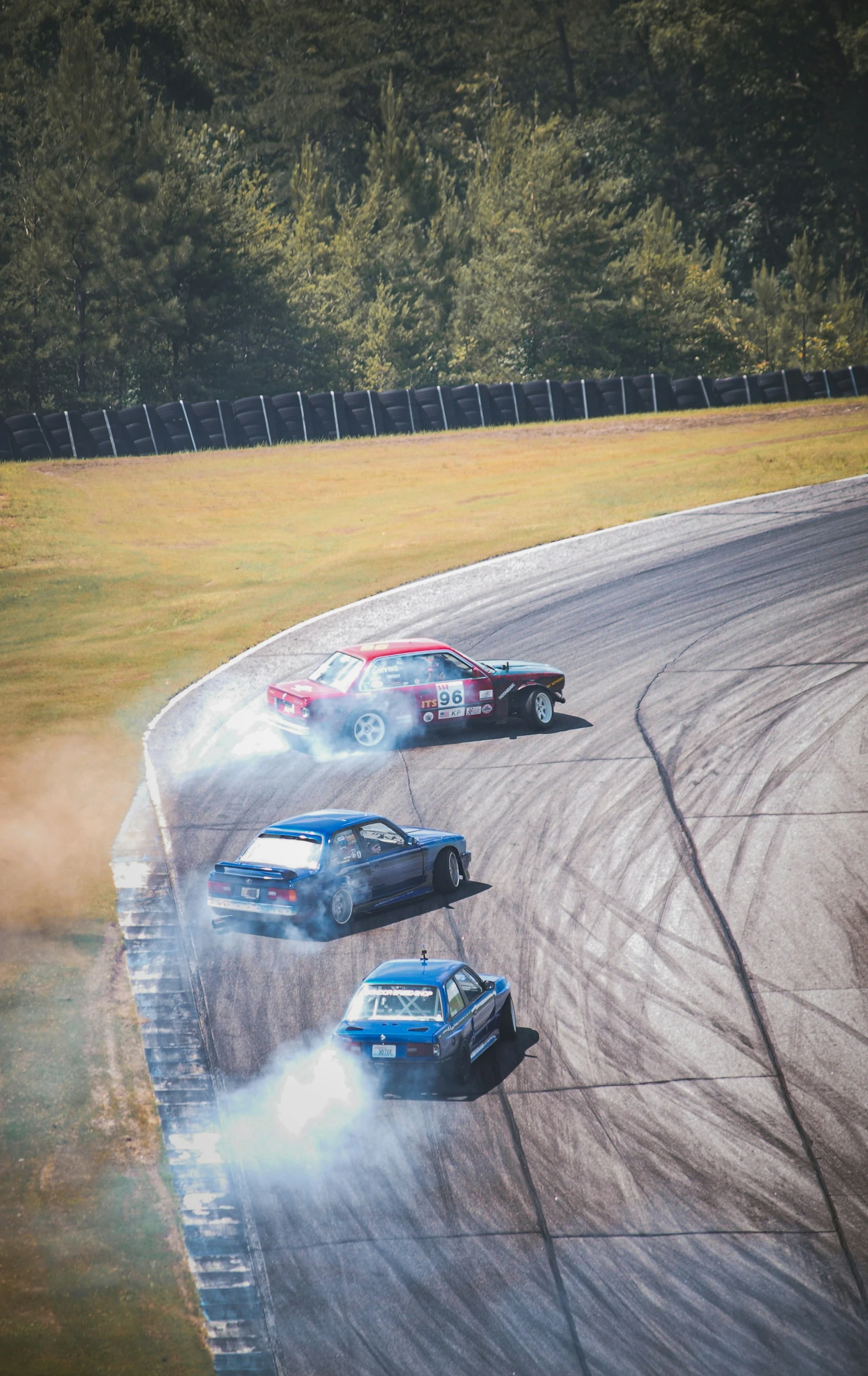 three cars in a race on a dirt track