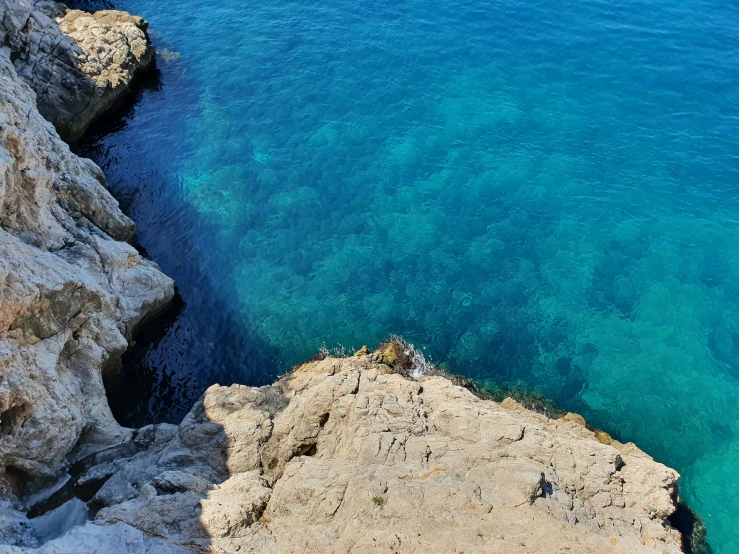 a rocky beach with bright blue water under it