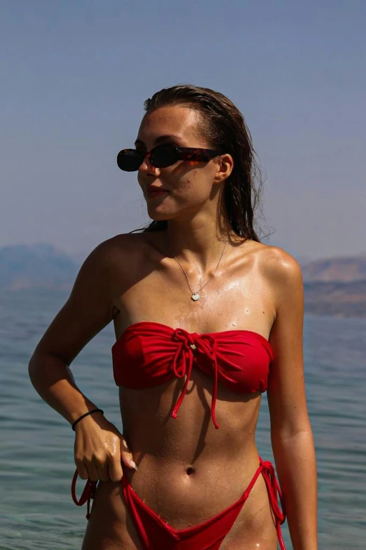 a beautiful woman in red bathingsuit standing on a beach