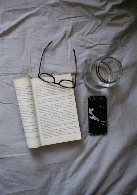 an open book and glasses on top of a bed