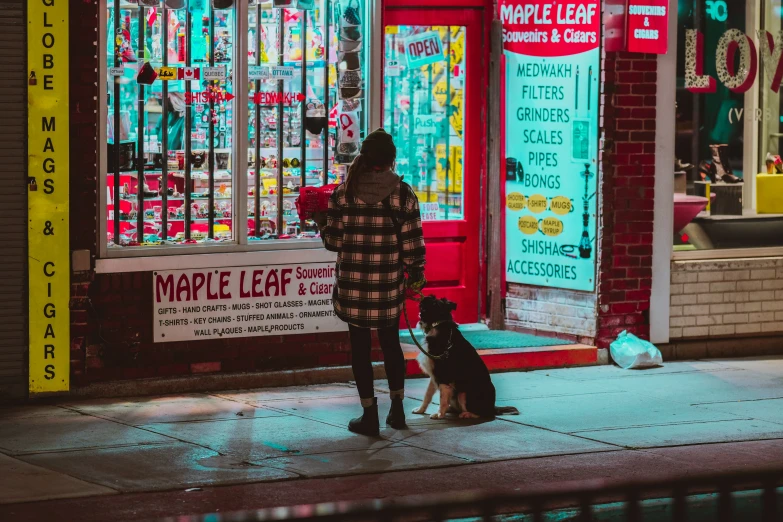 a woman is looking in the store window with two dogs outside