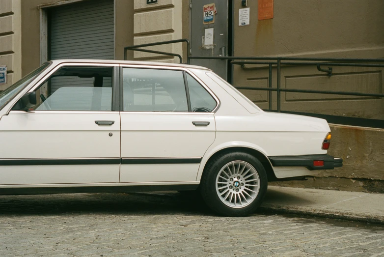 a white bmw parked in front of a garage door