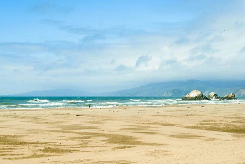 the sky is over the beach where birds are flying