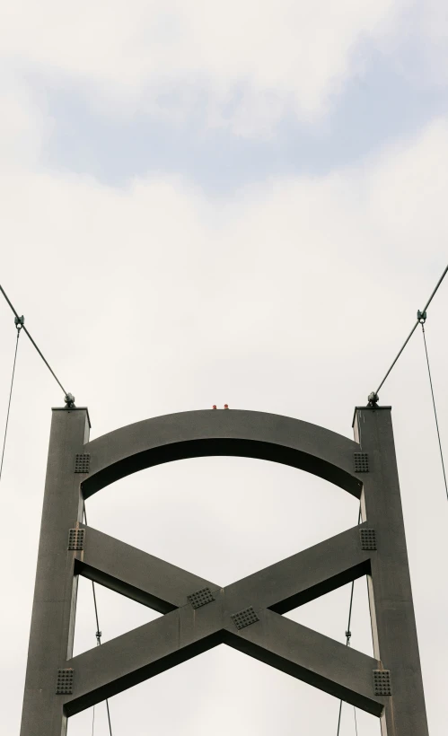 a man is flying above a bridge and holding on to wires