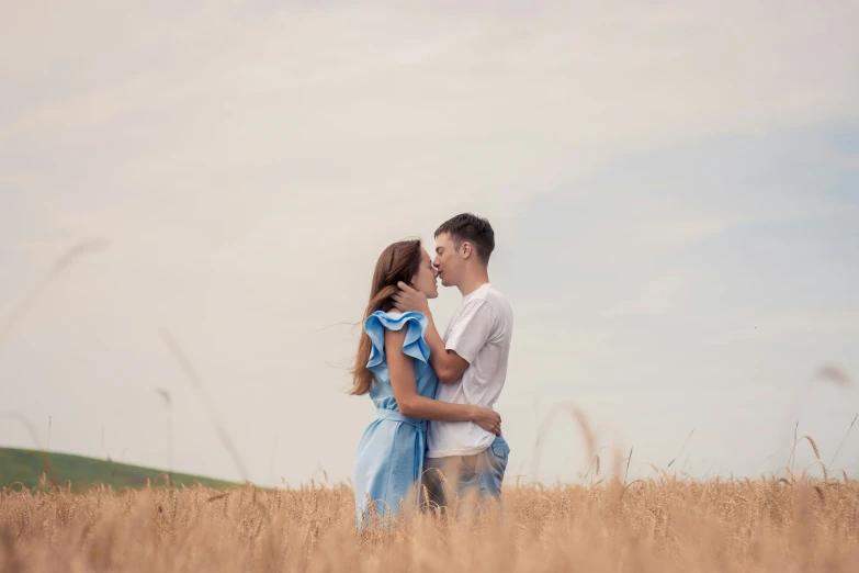 a couple stands in tall grass looking at each other