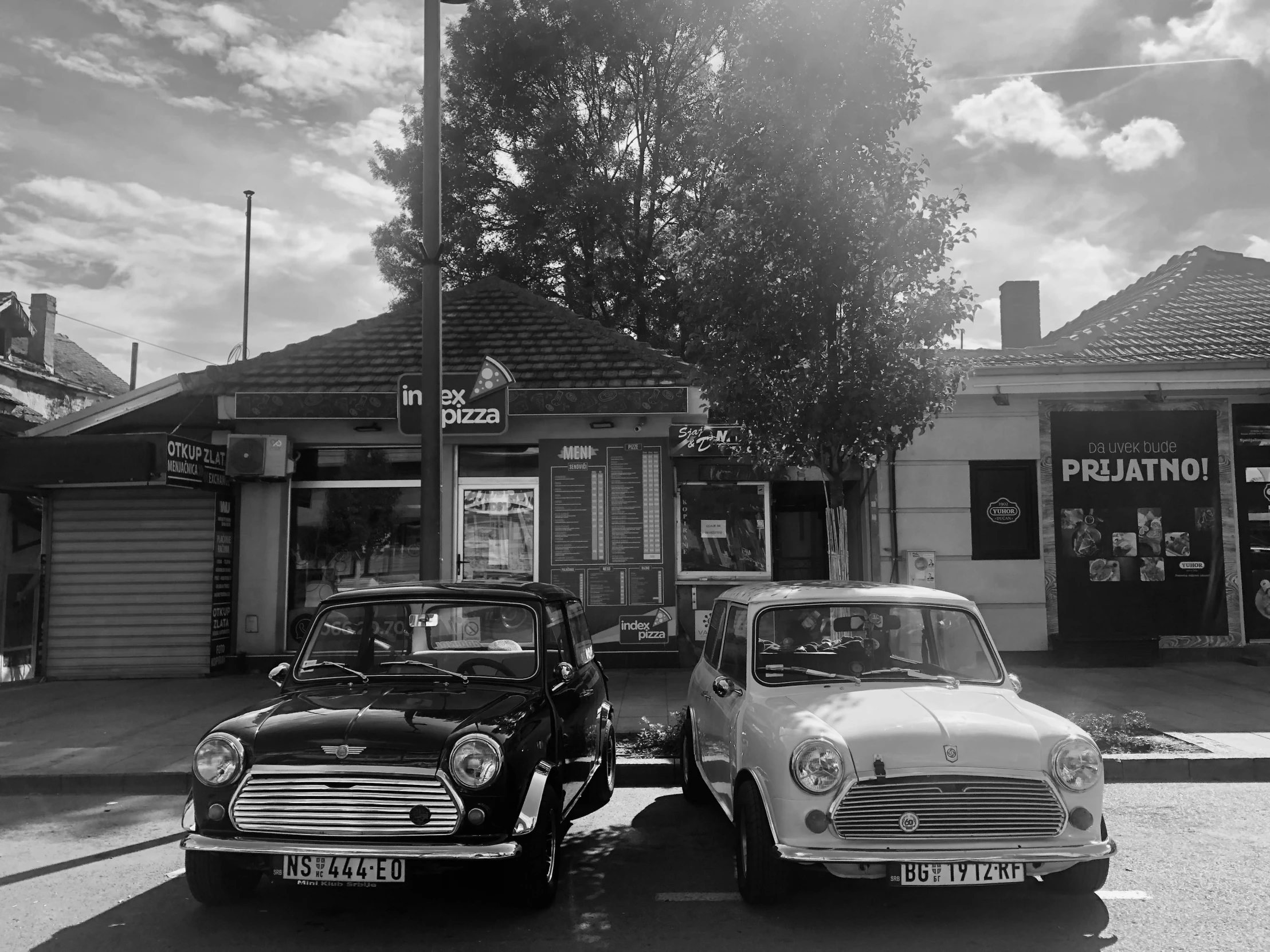 a couple of old school cars are parked in front of a store