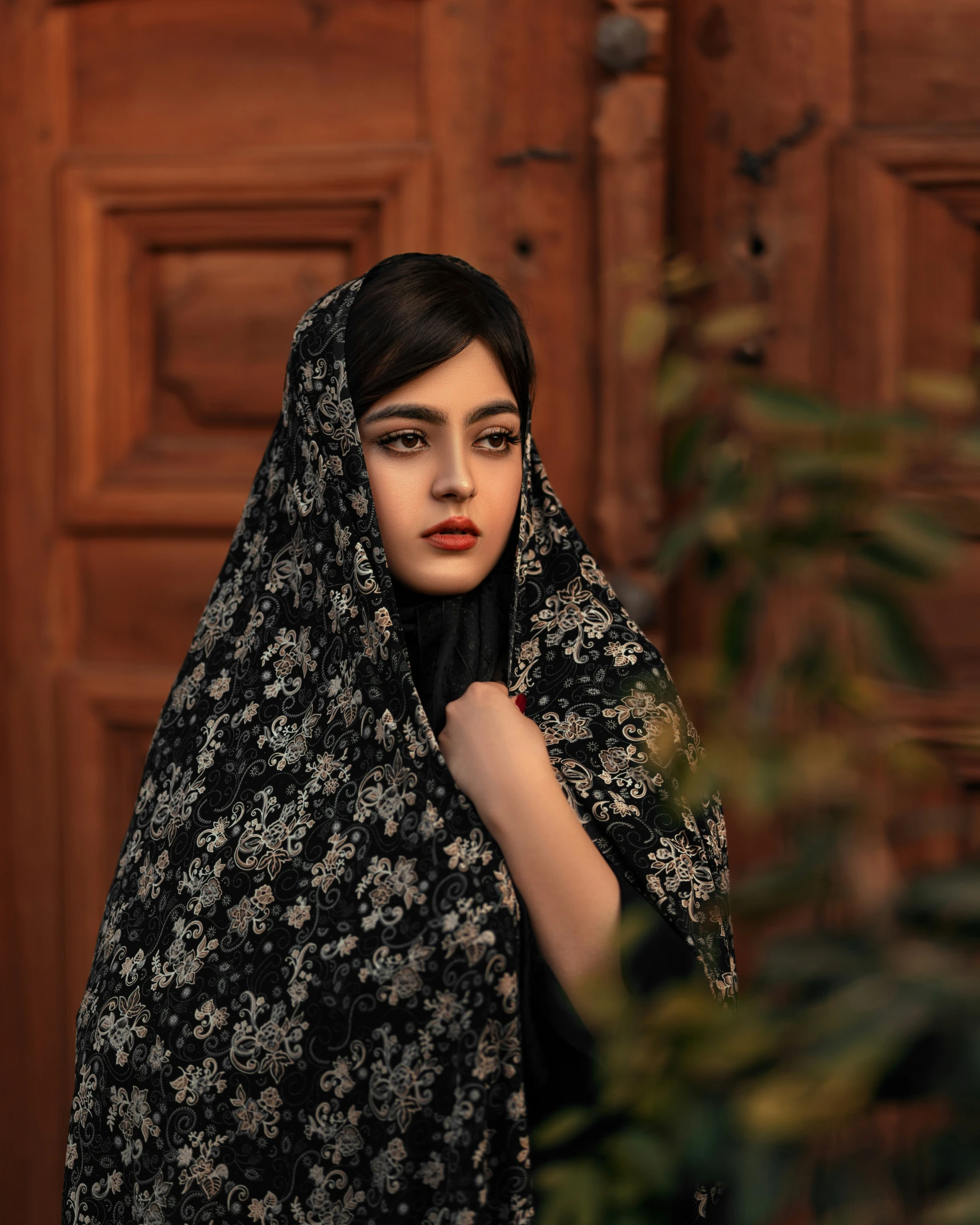 a model is shown in front of a wooden door with a scarf dd over her head