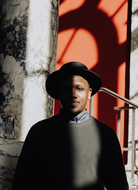 a man wearing a hat standing in front of a building