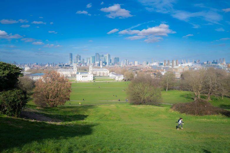 two people walk through an open field towards the city