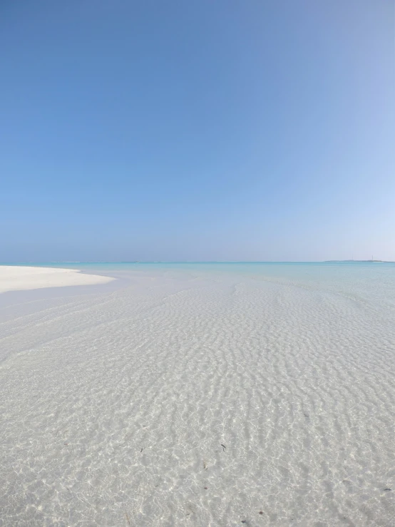 blue and white sky over a beach with small waves