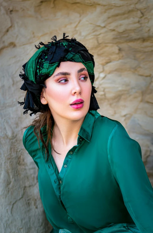 a woman wearing a green blouse and black head scarf