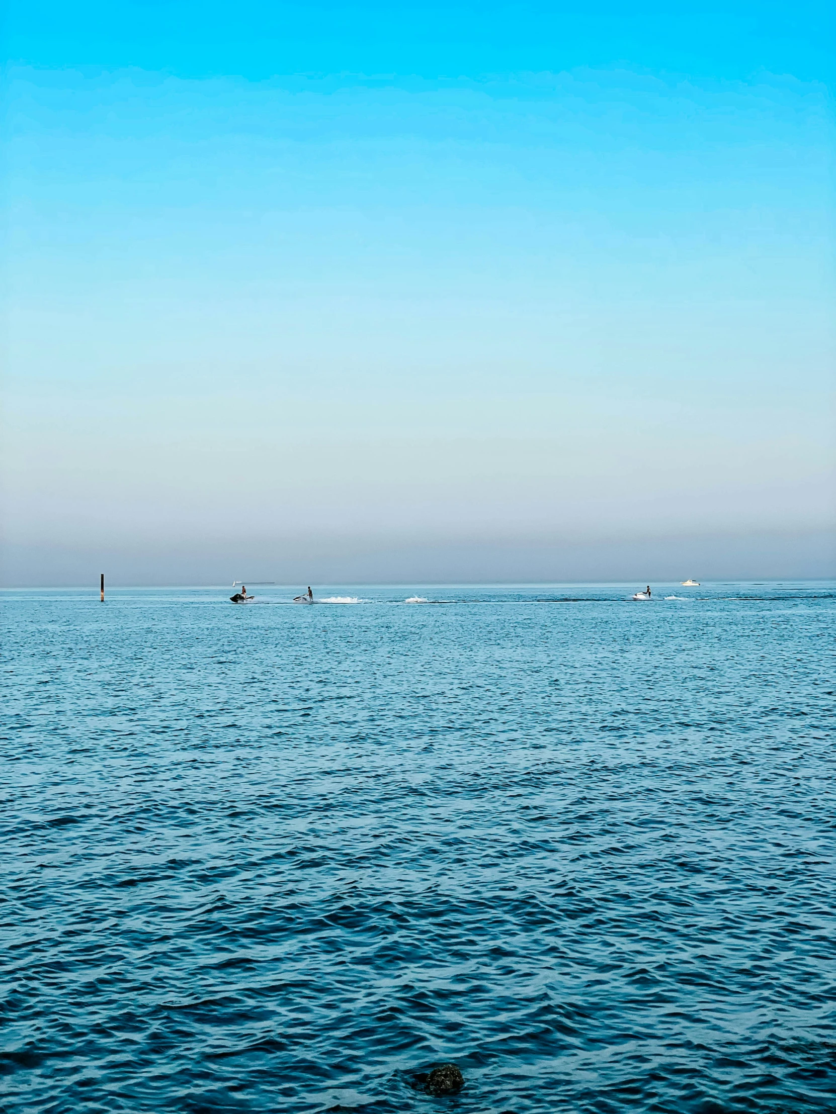 the horizon of a body of water with boats in the distance