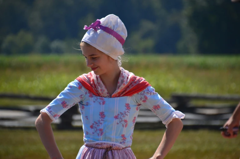 the little girl is wearing a dress and a hat