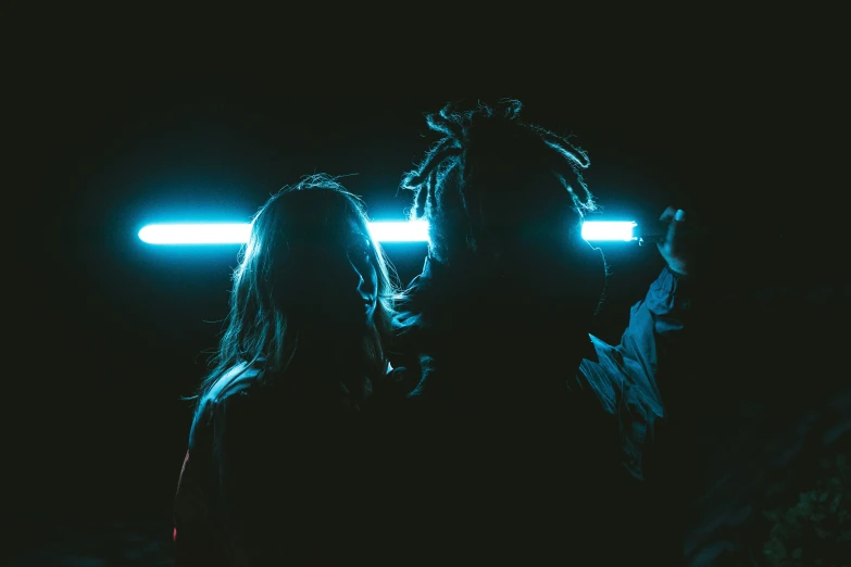 two people are standing side by side and one is illuminated up by lights