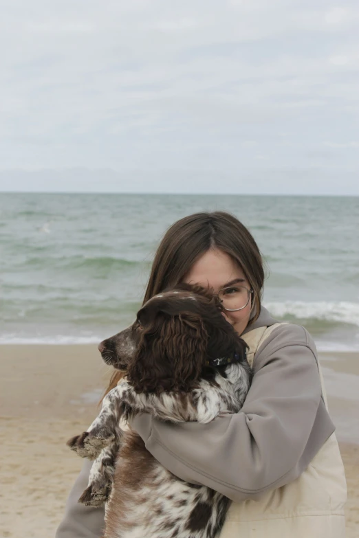 a woman is holding her dog on the beach