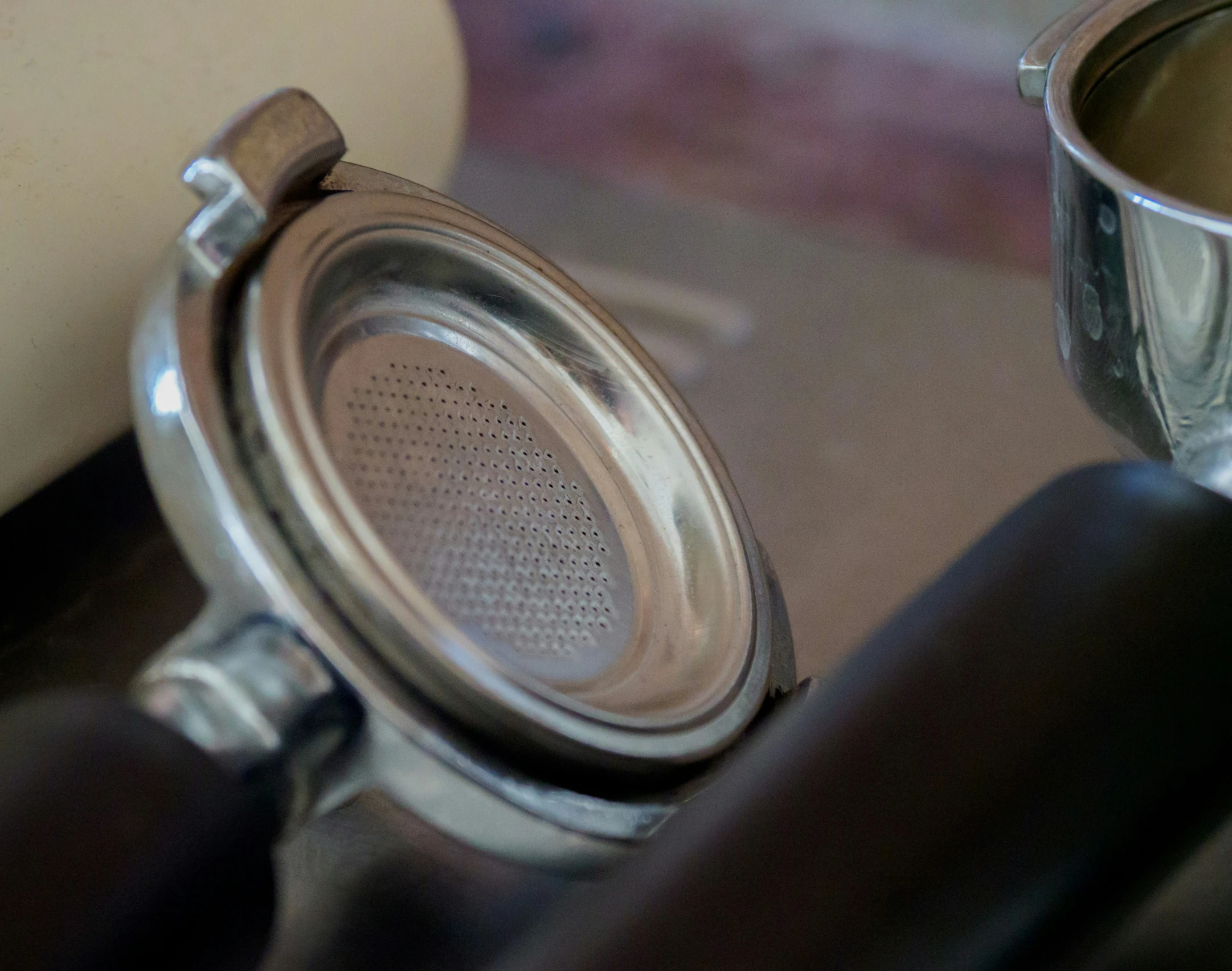 a strainer sitting on top of a table next to a metal cup